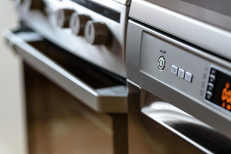Primer plano de un aparato de cocina de acero inoxidable con perillas de control y pantallas digitales.