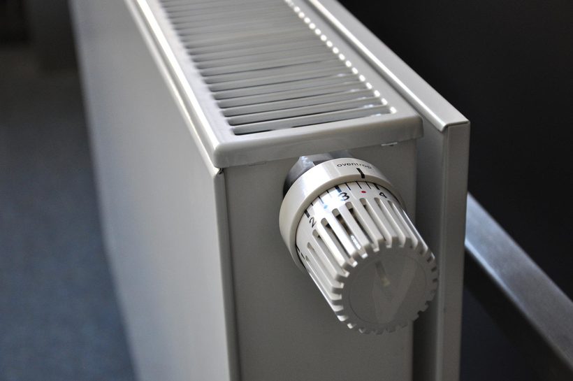 Primer plano de un radiador blanco con una perilla de termostato ajustable en posición baja.
