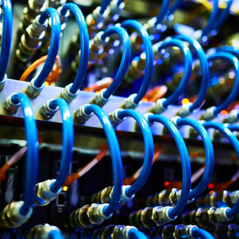 Primer plano de cables de red azules conectados a los puertos de un rack de servidores.
